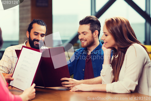 Image of smiling friends discussing menu at restaurant