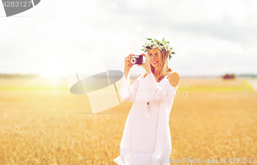 Image of happy woman with film camera in wreath of flowers