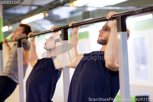 Image of group of young men doing pull-ups in gym