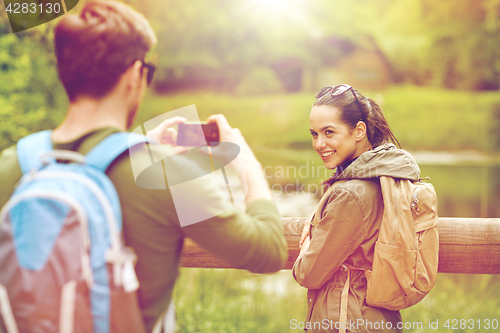 Image of couple with backpacks taking picture by smartphone