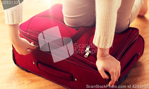 Image of close up of woman packing travel bag for vacation