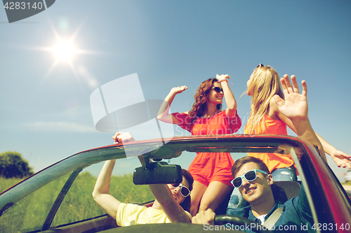 Image of happy friends driving in cabriolet car