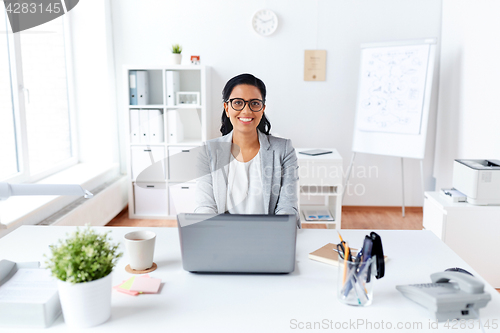 Image of happy businesswoman with laptop working at office