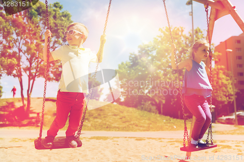 Image of two happy kids swinging on swing at playground