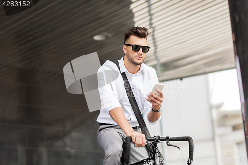 Image of man with bicycle and smartphone on city street