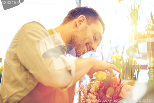 Image of smiling florist man making bunch at flower shop