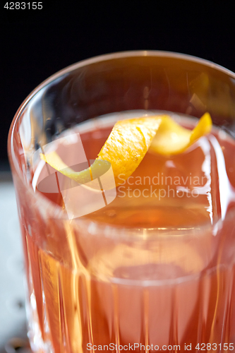 Image of close up of glass with orange cocktail at bar