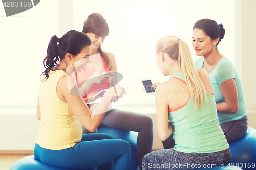 Image of happy pregnant women with gadgets in gym