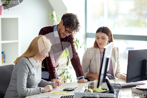 Image of happy business team with calculator at office