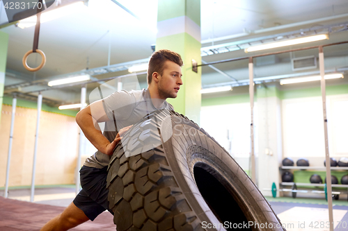 Image of man doing strongman tire flip training in gym