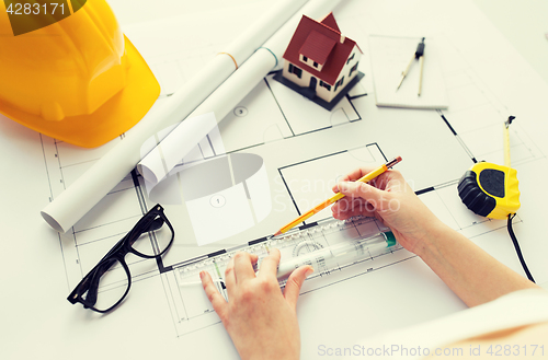 Image of close up of hands with ruler measuring blueprint