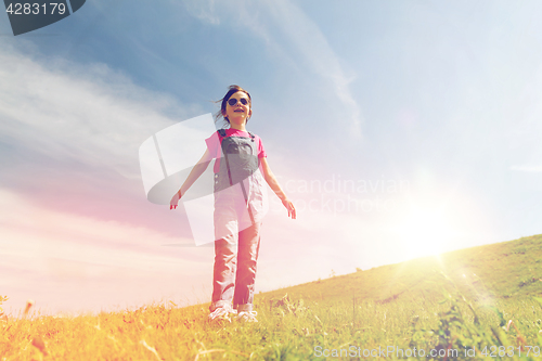 Image of happy little girl over green field and blue sky