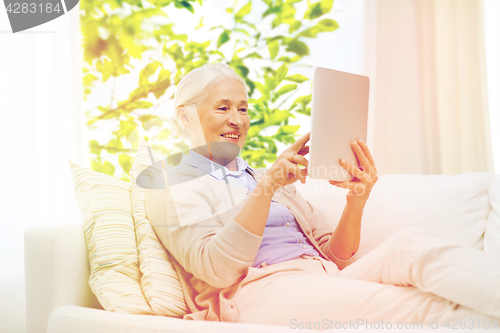 Image of happy senior woman with tablet pc at home