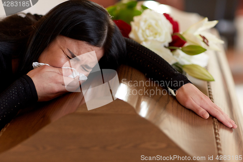 Image of woman with coffin crying at funeral in church