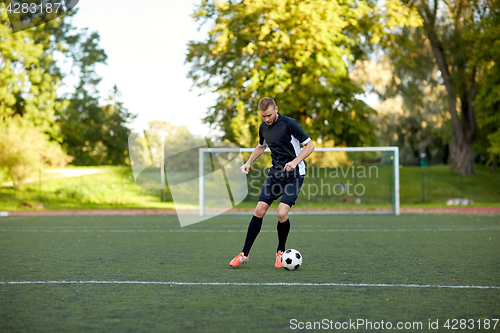 Image of soccer player playing with ball on football field