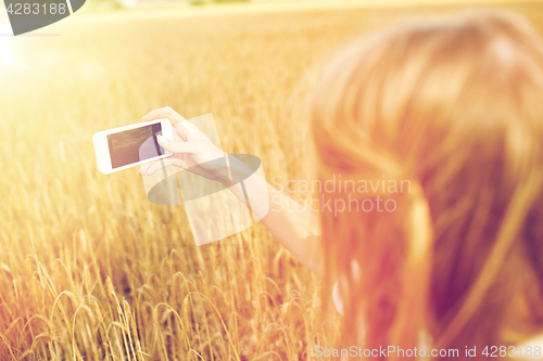 Image of close up of girl with smartphone on cereal field