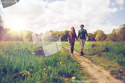 Image of happy couple with backpacks hiking outdoors