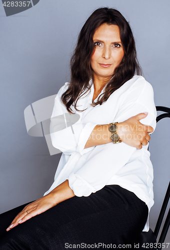 Image of pretty brunette confident mature woman sitting on chair in studi