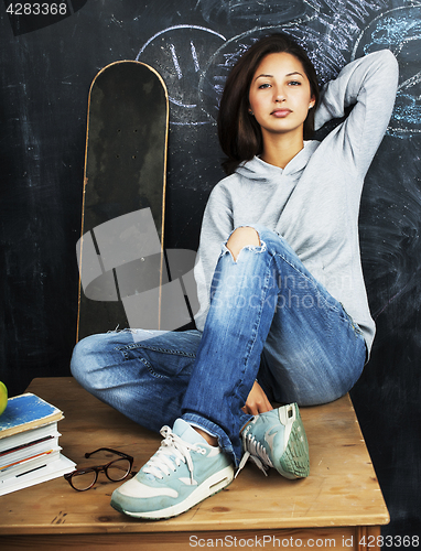 Image of young cute teenage girl in classroom at blackboard seating on ta