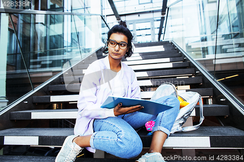 Image of young cute indian girl at university building sitting on stairs 