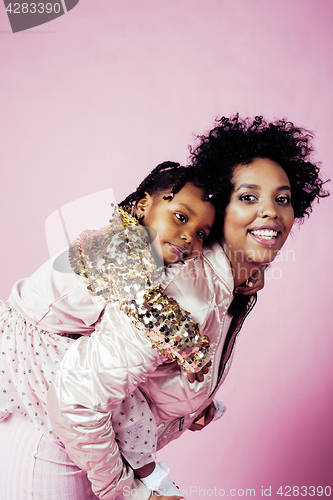 Image of young pretty african-american mother with little cute daughter hugging, happy smiling on pink background, lifestyle modern people concept 