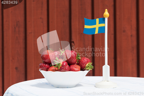 Image of Bowl with fresh strawberries and a swedish flag