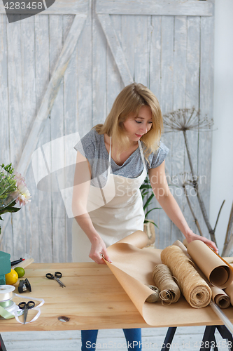 Image of Young florist cutting paper wrapping