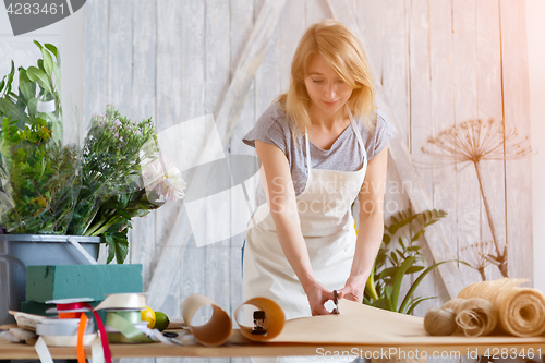 Image of Florist girl cuts wrapping paper