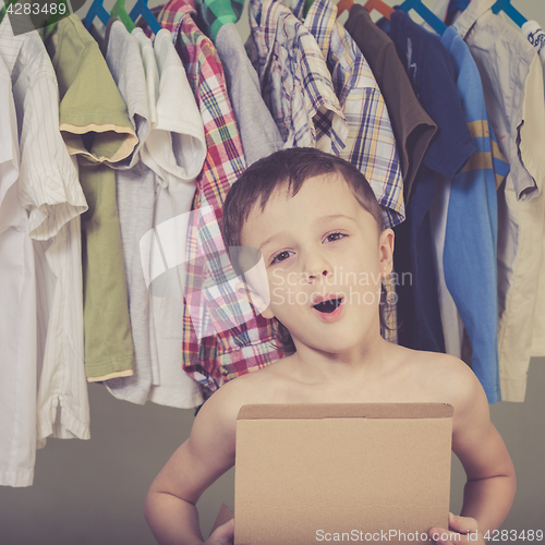 Image of portrait of a little boy standing near a hanger with clothes