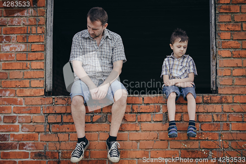 Image of Portrait of sad little boy and father.