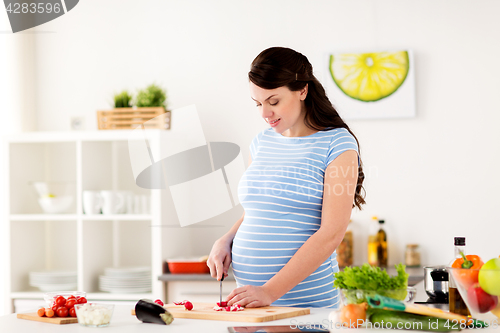 Image of pregnant woman cooking vegetables at home