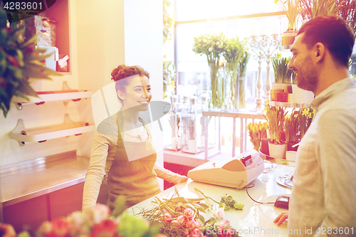 Image of smiling florist woman and man at flower shop