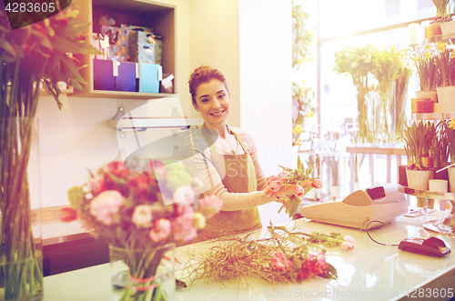 Image of smiling florist woman making bunch at flower shop