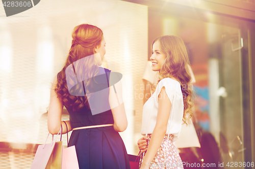 Image of happy women with shopping bags at shop window