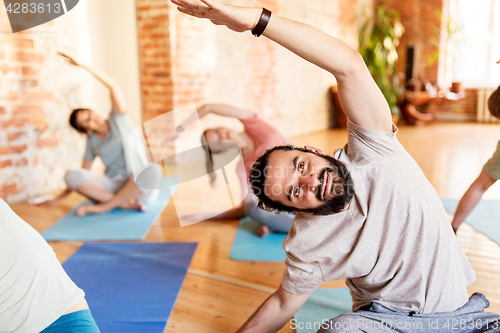 Image of group of people doing yoga exercises at studio