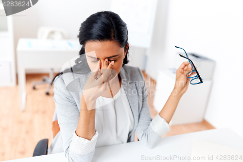 Image of businesswoman rubbing tired eyes at office