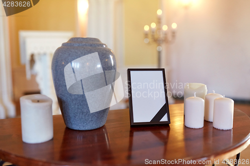 Image of photo frame, cremation urn and candles in church