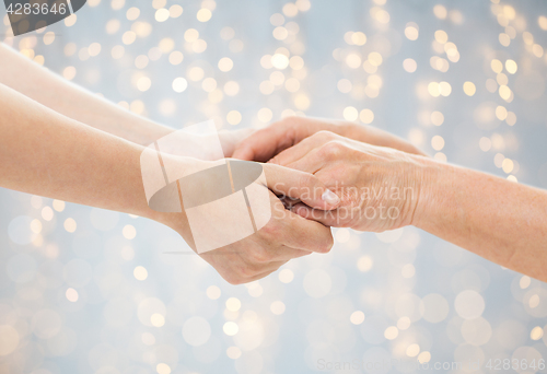 Image of close up of senior and young woman holding hands