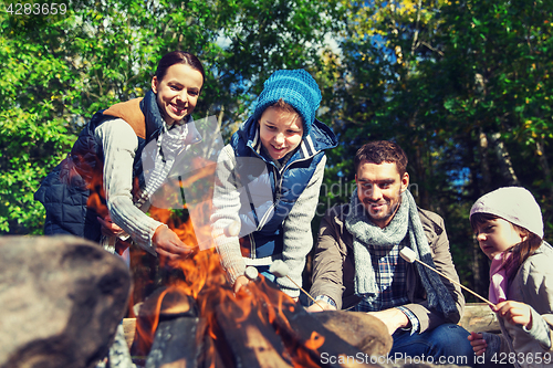 Image of happy family roasting marshmallow over campfire