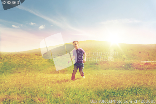 Image of happy little boy running on green field outdoors