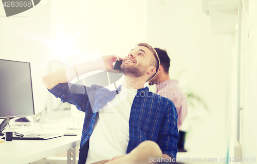 Image of happy creative man calling on cellphone at office