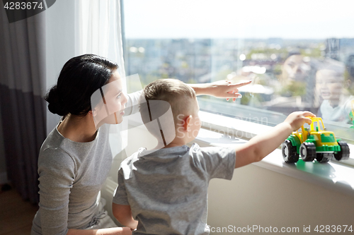 Image of mother and son looking through window at home