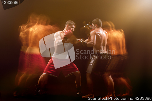 Image of The two male boxers boxing in a dark studio