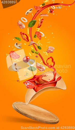 Image of Tasty pizza and falling ingredients on orange background