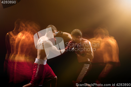 Image of The two male boxers boxing in a dark studio