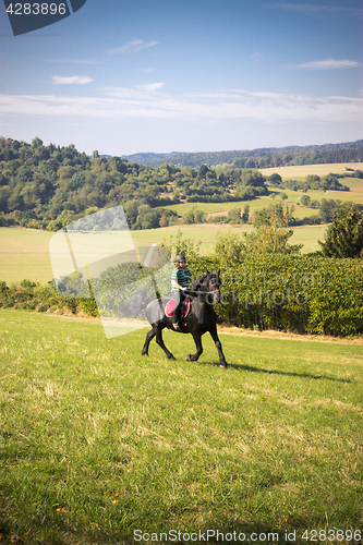 Image of Beautiful young woman rides her black Horse 