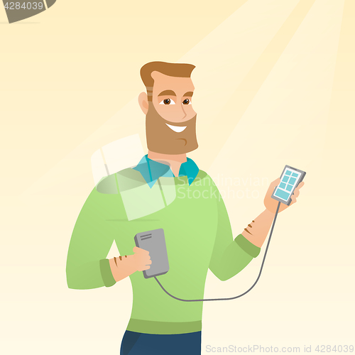 Image of Man reharging smartphone from portable battery.