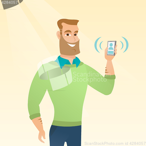 Image of Young caucasian man holding ringing mobile phone.