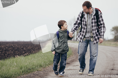 Image of Father and son walking on the road at the day time. 