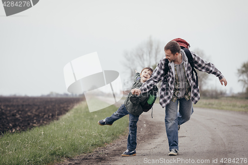 Image of Father and son walking on the road at the day time.